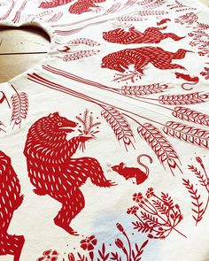 a red and white table cloth with an animal design on it, sitting on a wooden surface