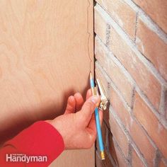 a person holding a pencil in front of a brick wall with the word handyman written on it