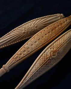 two carved wooden spoons sitting next to each other on a black tableclothed surface