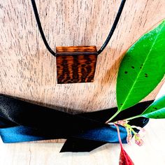 a wooden necklace with the word love on it and a black ribbon tied around it