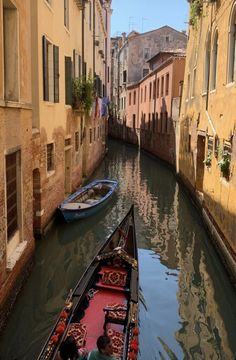 two boats are parked along the side of a narrow canal in an old city with buildings on both sides