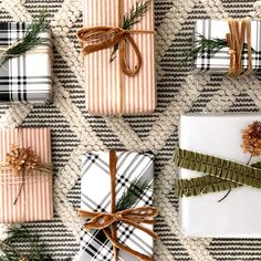 presents wrapped in plaid and tied with brown ribbon are sitting on the floor next to pine branches