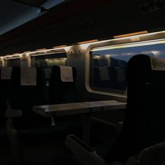 the interior of a subway train at night with empty seats and tables on each side