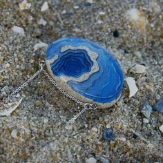 A ring-shaped reef, island, or chain of islands formed of coral The Atoll pendant has been carefully handmade from bonded beach sand, ultramarine or aqua blue resin and metal pigments with a high-gloss polished finish. Two eye screws connect the piece to a fine cable link chain. All metal parts are rhodium plated. Each purchase from BoldB's Aqua Collection will help provide one year of safe water to one person in need through BoldB's support of Water.org, an international nonprofit organisation. Ocean-inspired Blue Pendant Jewelry, Unique Blue Jewelry With Adjustable Chain, Blue Pendant Jewelry For Beach, Blue Gemstone Jewelry For The Beach, Blue Gemstone Necklace For Beach, Ocean-inspired Blue Round Pendant Jewelry, Blue Jewelry With Adjustable Chain For Beach, Blue Beach Jewelry With Adjustable Chain, Oval Blue Agate Jewelry