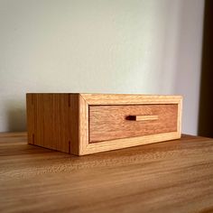 a wooden box sitting on top of a table next to a white wall in the background