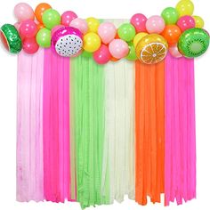 an assortment of colorful balloons and streamers on a white backdrop with oranges, limes, and straws