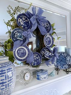 a blue and white wreath on top of a mantle with vases next to it