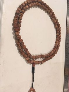 "Bodhi seed mala necklace made of 108 12mm beads with a Bodhi seed guru bead and an adjustable knot that allows you to change the length and tightness of the beads. Bodhi seeds are usually not polished so they are a solid color with small ridges or veins. Bodhi in Sanskrit translates to \"enlightened\" or \"awakened,\" therefore the Bodhi seed means \"enlightened seed.\" Bodhi is also a term in Buddhism to reflect a Buddha's understanding of the true nature of things. Many Buddhist wear the Bodh Adjustable Necklace With Oval Beads For Meditation, Brown Beaded Necklaces For Meditation And Festivals, Spiritual Beaded Necklace With 108 Round Beads, 108 Beads Round Beaded Necklaces For Rituals, Adjustable Spiritual Beaded Necklaces For Meditation, Spiritual Necklaces With Large Adjustable Beads, Holistic Necklaces With 8mm Beads For Festivals, Healing Mala With Round Beads For Festivals, Adjustable Beaded Mala For Healing