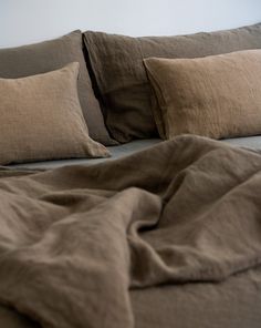 an unmade bed with brown linens and pillows