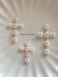 the cross is made out of glass beads and has pink, white and gold accents