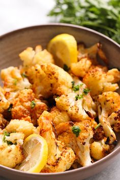 a bowl filled with cauliflower and lemon wedges