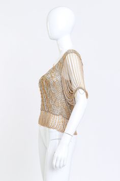 Loris Azzaro gained international fame for dressing celebrities like Tina Turner in his glimmering textiles. Items such as this gold metallic knit top featuring draped chain details have since become fashionista collectors pieces. Shimmering sheer short sleeve knit and chain top Gold, silver Circa early 1970s Lamé woven knit & fine spiral chain drape detail Scoop neckline Chandelier chain sleeves Criss-cross draped hem Pullover style No fabric contents - silk/wool mix, metallic fibers Loris Azzaro label, made in France Very good vintage condition, stained label Estimated Size: S Measurements ~has up to 4* of stretch Bust: 28"-32"Waist: 25"-29" Length (Centre Front to Waistband): 10.5"Waistband (Chain Drop): 4"Length (Centre Back): 16"Shoulder-to-Shoulder: 16"Sleeve Length: 8" Sleeve Openin Gold Embellished Tops For Night Out, Elegant Short Sleeve Mesh Top For Evening, Elegant Gold Embellished Top, Fitted Glamorous Gold Tops, Gold Short Sleeve Top For Evening, Chic Gold Short Sleeve Top, Gold Sequined Short Sleeve Top, Gold Short Sleeve Top With Sequins, Gold Sequin Short Sleeve Top