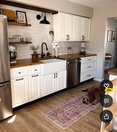 a dog laying on the floor in a kitchen with white cabinets and stainless steel appliances