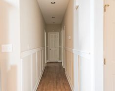 an empty hallway with white walls and wood floors