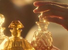 a person holding an object in their hand next to other items on a table with gold trimmings