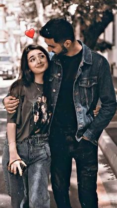 a man and woman standing next to each other in the street with a red heart on their forehead