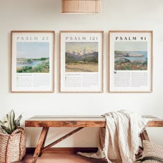 three framed pictures hang on the wall above a bench with a blanket and potted plant