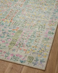 an area rug with various colored flowers and leaves on the floor in front of a wooden floor