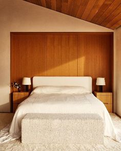 a bedroom with a bed and two lamps on either side of the bed, along with wood paneling