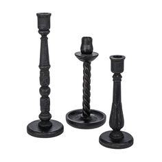 three black candlesticks are standing next to each other on a white background,