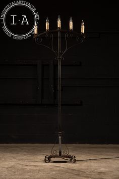 an iron candelabra with five candles on it in front of a black wall