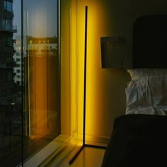 a bed sitting next to a window in a room with a lamp on top of it