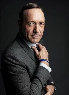 a man in a suit and tie posing for a photo with his hands on his chest