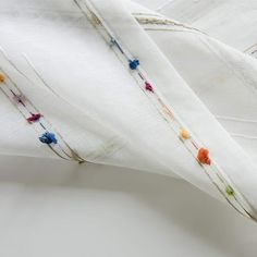 two white linens with colorful thread sprinkles on them, one folded and the other unzipped