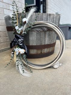 a wooden barrel with some flowers and feathers on it next to a roped planter