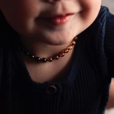 a close up of a child wearing a necklace with beads on it's neck