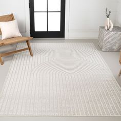 a white rug with an abstract design on the floor next to a chair and window