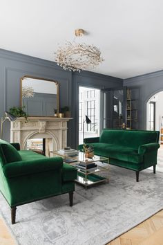 a living room filled with green couches and chairs next to a fire place in front of a fireplace