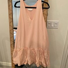 a pink top hanging on a hanger in front of a mirror with an open door