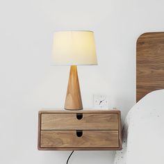 a nightstand with a lamp on it next to a bed