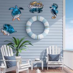 there are three chairs on the porch with sea turtles and life preservers mounted to the wall