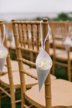 an arrangement of chairs with white flowers tied to the back and one flower in a cone