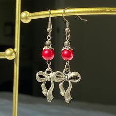 Crafted from my grandmother, Susie, these earrings feature moody red charm and bow. Add a touch of timeless elegance to your jewelry collection with these beautifully crafted earrings. They make a perfect gift for someone special or a delightful treat for yourself. Details: Second image is more accurate coloring Materials: Stainless Steel, red glass pearls Charm: Bow Design: Handmade Style: Elegant and versatile Care Instructions: To keep your earrings looking their best, gently clean with a sof Adjustable Earrings For Christmas Gift, Adjustable Earrings As A Christmas Gift, Elegant Christmas Jewelry With Dangle Shape, Elegant Handmade Earrings For Valentine's Day, Elegant Holiday Earrings For Festive Occasions, Elegant Christmas Drop Earrings, Elegant Holiday Jewelry With Matching Earrings, Elegant Festive Holiday Earrings, Elegant Holiday Festive Earrings