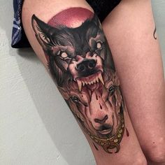 a woman's thigh with a wolf tattoo on it and chains around her ankles