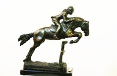 a bronze statue of a jockey riding a horse on a black base with a white background