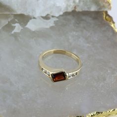 14K Yellow Gold Garnet and Diamond Ring, garnet rectangular offset 4 round diamond side stones, .25 inch across, Ring size 6.75, Circa 1970, 3.4 grams SKU # BB256R27 Most rings are sizable for a small fee. If the ring you are considering is the incorrect size contact us for a quote. This listing contains photographs of the actual item you will receive. Our items are in excellent condition with little or no signs of wear and many are one of a kind pre-owned estate finds. Please look closely at th Three Stone Rectangular Jewelry Gift, Rectangular Three Stone Jewelry Gift, Rectangular Three Stone Jewelry As A Gift, Classic Multi-stone Baguette Cut Rings, Rectangular Three Stone Diamond Jewelry, Three Stone Rectangular Diamond Jewelry, Rectangular Three Stone Rings For Anniversary, Rectangular Yellow Gold Jewelry With Accent Stones, Modern Garnet Jewelry For Anniversary