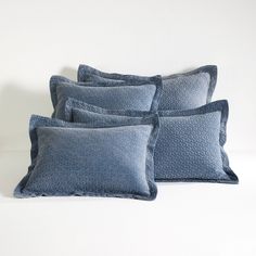 four blue pillows sitting on top of a white bed