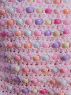 a crocheted blanket with pastel colored dots on it