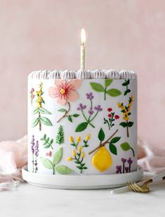 a white cake with flowers and leaves on it sitting on a plate next to a fork