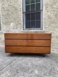 a large wooden dresser sitting on the side of a road next to a building with a barred window