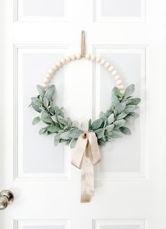 a white door with a wreath on it and a ribbon hanging from the front door