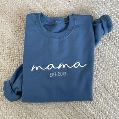 *Sample shown with White thread on Indigo sweatshirt* This cozy and stylish crewneck is the perfect custom gift for any mom. Whether you're a new mom looking to celebrate your little one's arrival or an experienced mama proud of your motherhood journey, this sweatshirt is a beautiful way to showcase your mama status. Crafted with love and care, this sweatshirt features custom embroidery of your Mama EST date. The embroidered date adds a personal touch that celebrates the special milestone in you Winter Crew Neck Sweatshirt With Name Print, Casual Crew Neck Sweatshirt For Mother's Day, Cotton Crew Sweatshirt With Name Print, Casual Crew Neck Sweater With Name Print, Casual Crew Neck Sweatshirt As Gift, Relaxed Fit Name Print Sweatshirt Gift, Customizable Casual Sweatshirt For Gift, Customizable Casual Sweatshirt For Gifts, Customizable Casual Sweatshirt As Gift