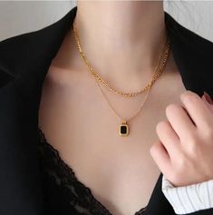 This necklace embodies a harmonious blend of textures and colors, with layers of lustrous gold stainless steel chains that elegantly cascade and culminate in a striking bezel-set black or white stone pendant. The contrast between the radiant gold and the deep black stone exudes a sense of intrigue and luxury, making it an ideal accessory for elevating any ensemble. With its versatile design and meticulous craftsmanship, this necklace becomes a symbol of refined elegance and modern style.Stainles Elegant Stainless Steel Chain Necklace, Elegant Gold Chain Necklace With Rectangular Pendant, Black Gold-plated Adjustable Chain Jewelry, Gold Chain Necklace With Rectangular Pendant, Formal Black Gold Plated Necklace, Formal Black Gold-plated Necklace, Black Pendant Necklace With Chain, Black Stainless Steel Clavicle Chain Necklace, Black Metal Pendant Chain Necklace