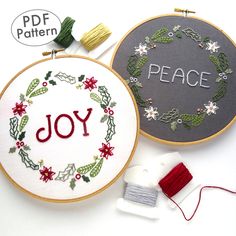 two embroidery hoops with the word joy on them next to some thread and needles