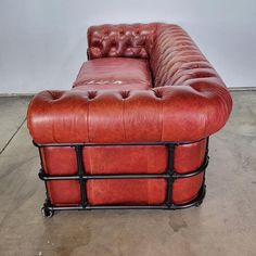 a red leather couch sitting on top of a metal frame