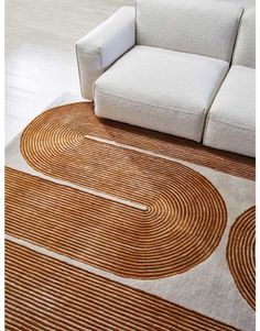 a white couch sitting on top of a wooden floor next to a brown and white rug